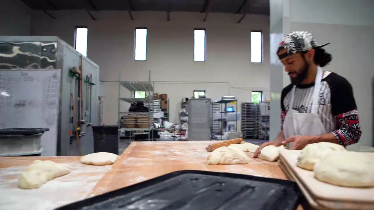 A baker dividing dough at the bench in the Hartford Baking Co bakery