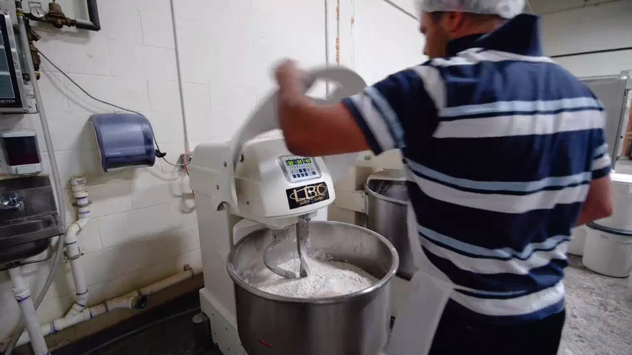 A baker filling a large mixer in the bakery