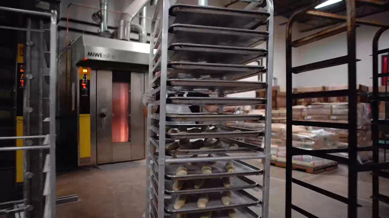 Rolling racks of trays in front of the bakery ovens